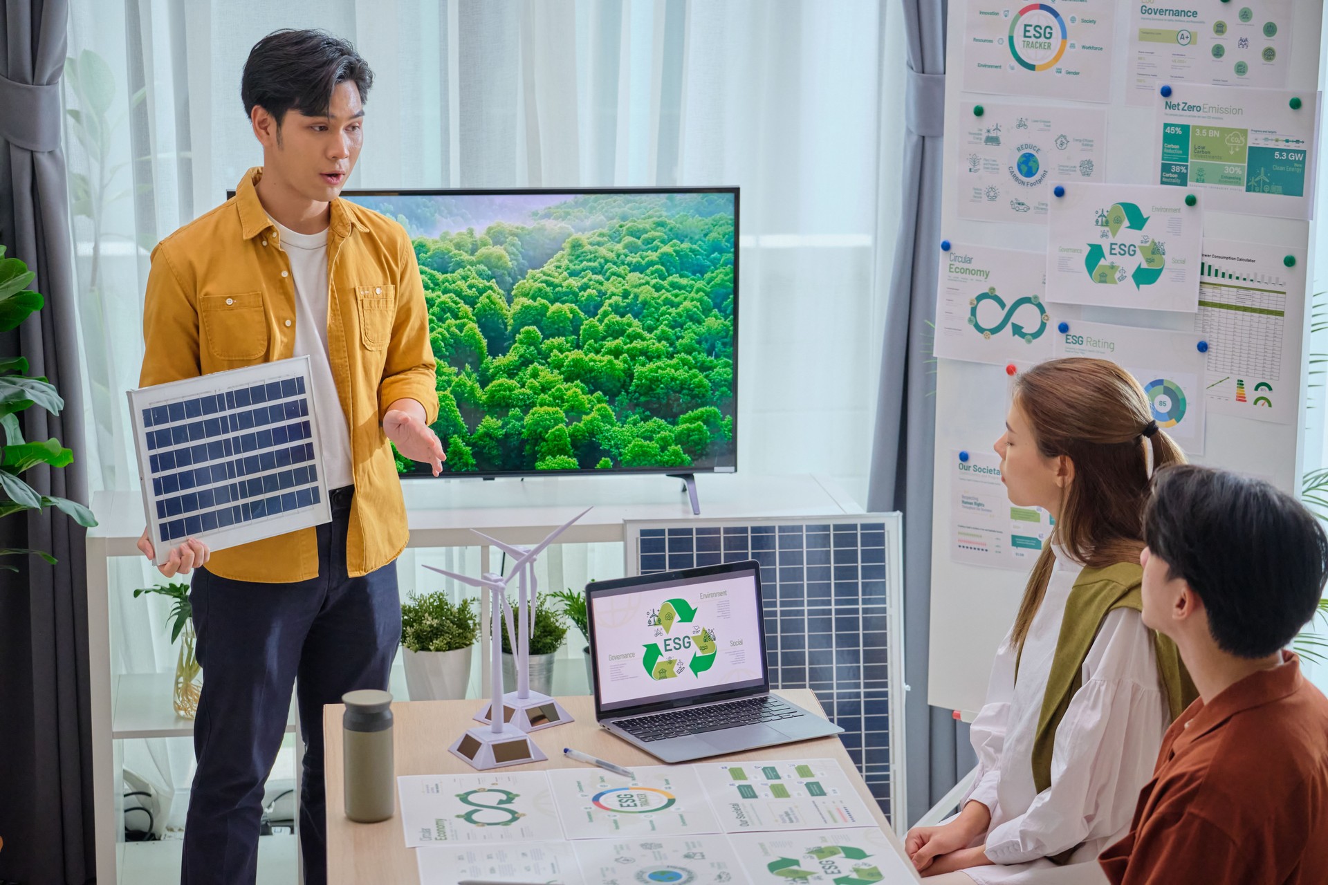 Group of Diversity business people having a ESG meeting environment, society and governance, discussing renewable energy with wind turbine  and solar panel at office